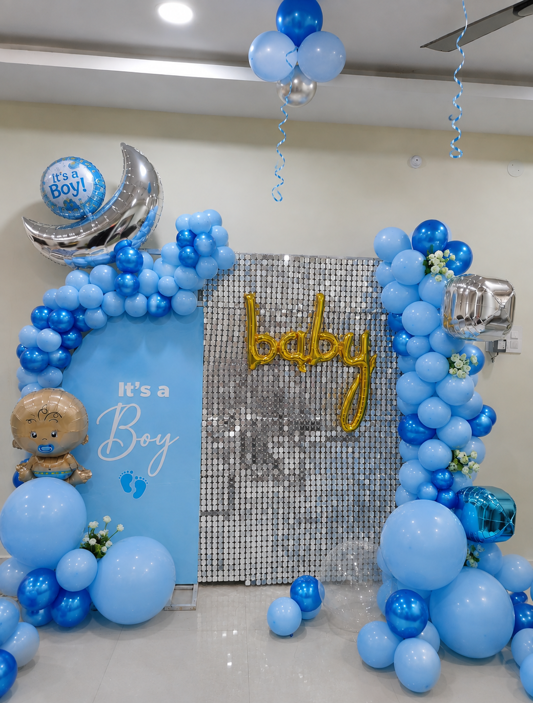 Celebrate the arrival of your little prince with our Premium Baby Boy Shower Decoration in Delhi NCR. This elegant blue and silver baby shower decoration features a stunning balloon arch, premium silver sequin backdrop, Baby foil letters, “It’s a Boy” balloons, baby-themed foil balloons, moon decoration and floral accents. Perfect for Baby Shower Decoration at Home, Baby Boy Shower Decoration, Godh Bharai Decoration, Welcome Baby Boy Decoration, Baby Welcome Decoration, Baby Shower Balloon Decoration, Baby Shower Party Decoration and Baby Boy Celebration Decoration. We provide customized balloon decoration in Delhi with options to change balloon colours, theme, baby name, text and decoration elements according to your choice. Ideal for celebrations in West Delhi, North Delhi, South Delhi, East Delhi and Delhi NCR.